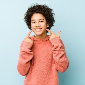 a child pointing to his smile