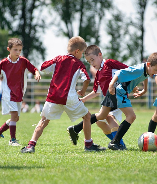 Youth athletes playing soccer on a field