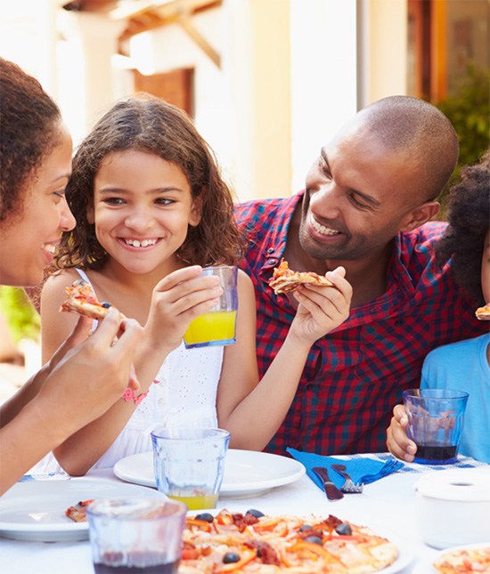 Family sharing slices of freshly made pizza at a table