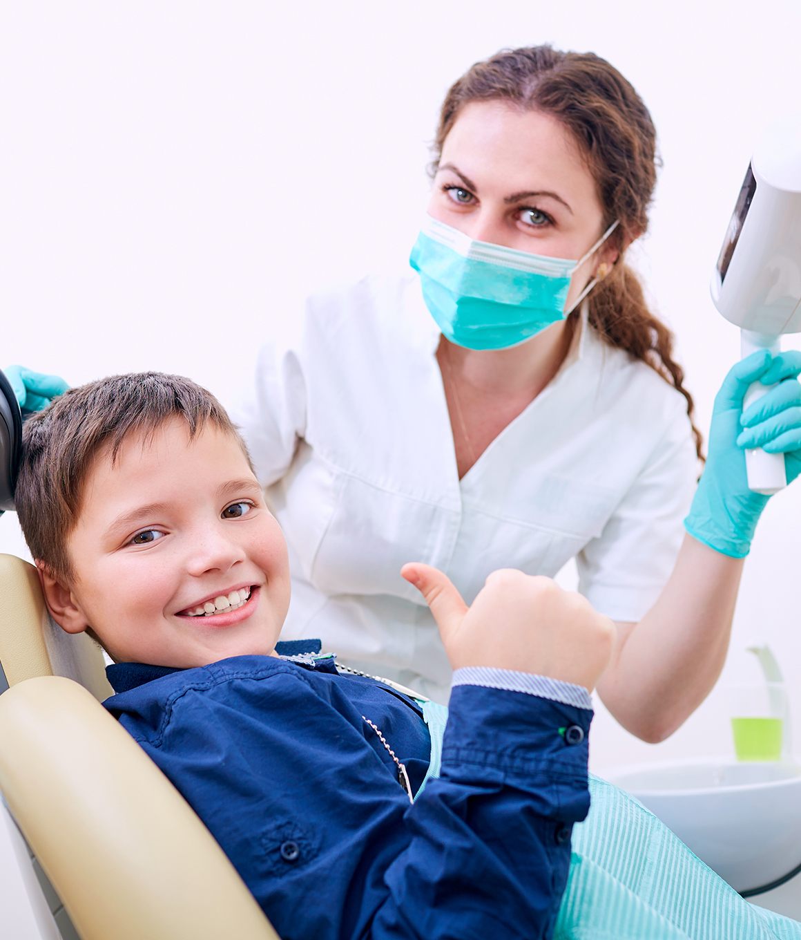 a kid visiting the dentist and giving a thumbs-up