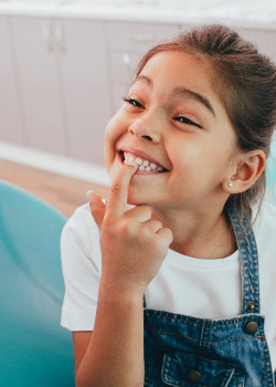 Smiling child pointing to their tooth
