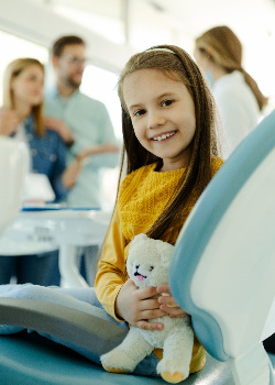 Child smiling while dentist and parents discuss treatment options