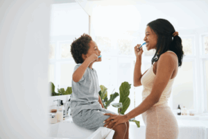 a parent and child brushing their teeth together