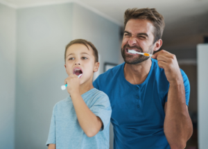 a parent and child brushing their teeth