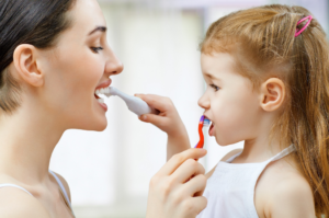 a child and parent brushing their teeth together